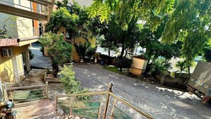 Um pátio com uma escadaria que leva a uma varanda, cercado por árvores e edifícios.
