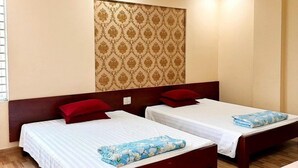 Quarto de hotel com duas camas de solteiro, cabeceiras de madeira, parede estampada e piso de madeira.