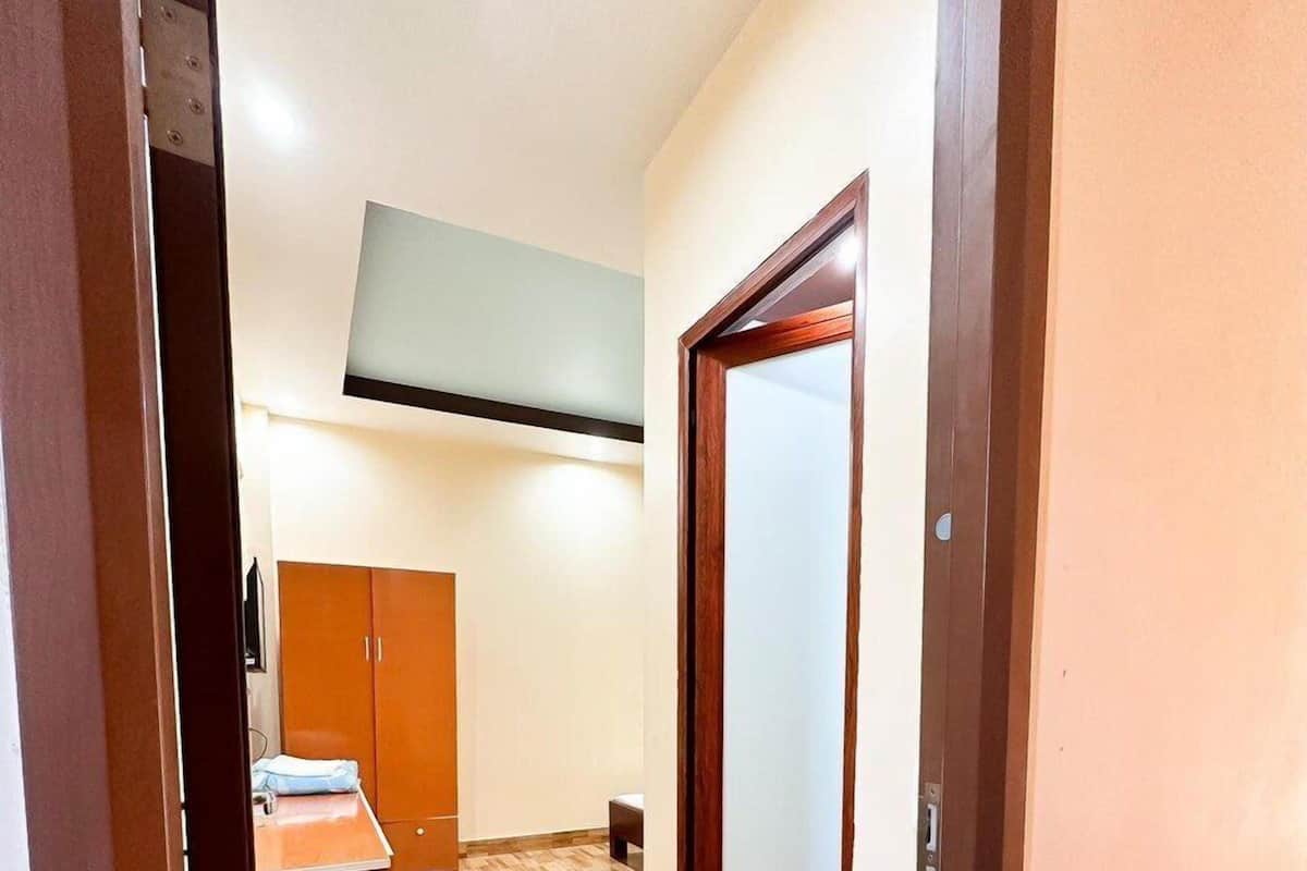 A hallway with a wooden wardrobe, a small table with a chair, and a door with a frosted glass panel.