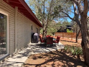 A house with a covered patio, a barbecue grill, and a fenced outdoor area with chairs and tables. - Luxe Serenity - Remodeled home walking distance from Chapel of the Holy Cross.
 (Sedona)