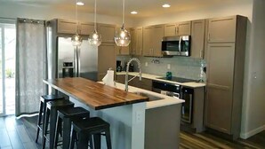 A modern kitchen with a central island, bar stools, stainless steel appliances, and pendant lighting. - Luxe Serenity - Remodeled home walking distance from Chapel of the Holy Cross.
 (Sedona)