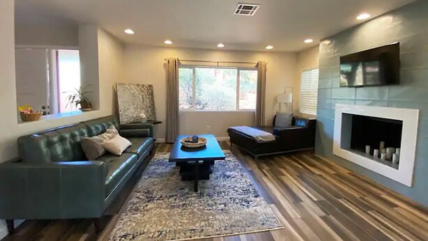 A living room with a green sofa, a blue coffee table, and a fireplace. - Luxe Serenity - Remodeled home walking distance from Chapel of the Holy Cross.
 (Sedona)