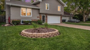 A two-story house with a front yard, a driveway, and a garage. - Paradise Pool House (Omaha)