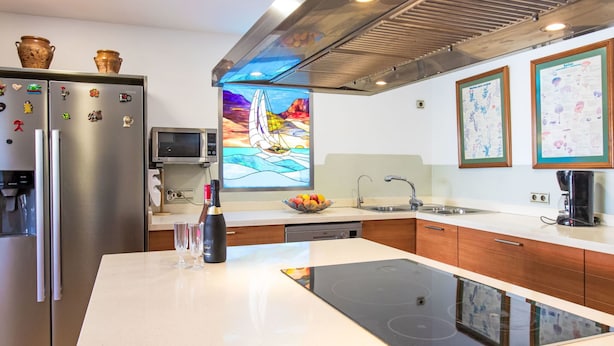 Una cocina moderna con un refrigerador de acero inoxidable, un microondas, un horno empotrado y una isla grande con una placa de inducción negra.
