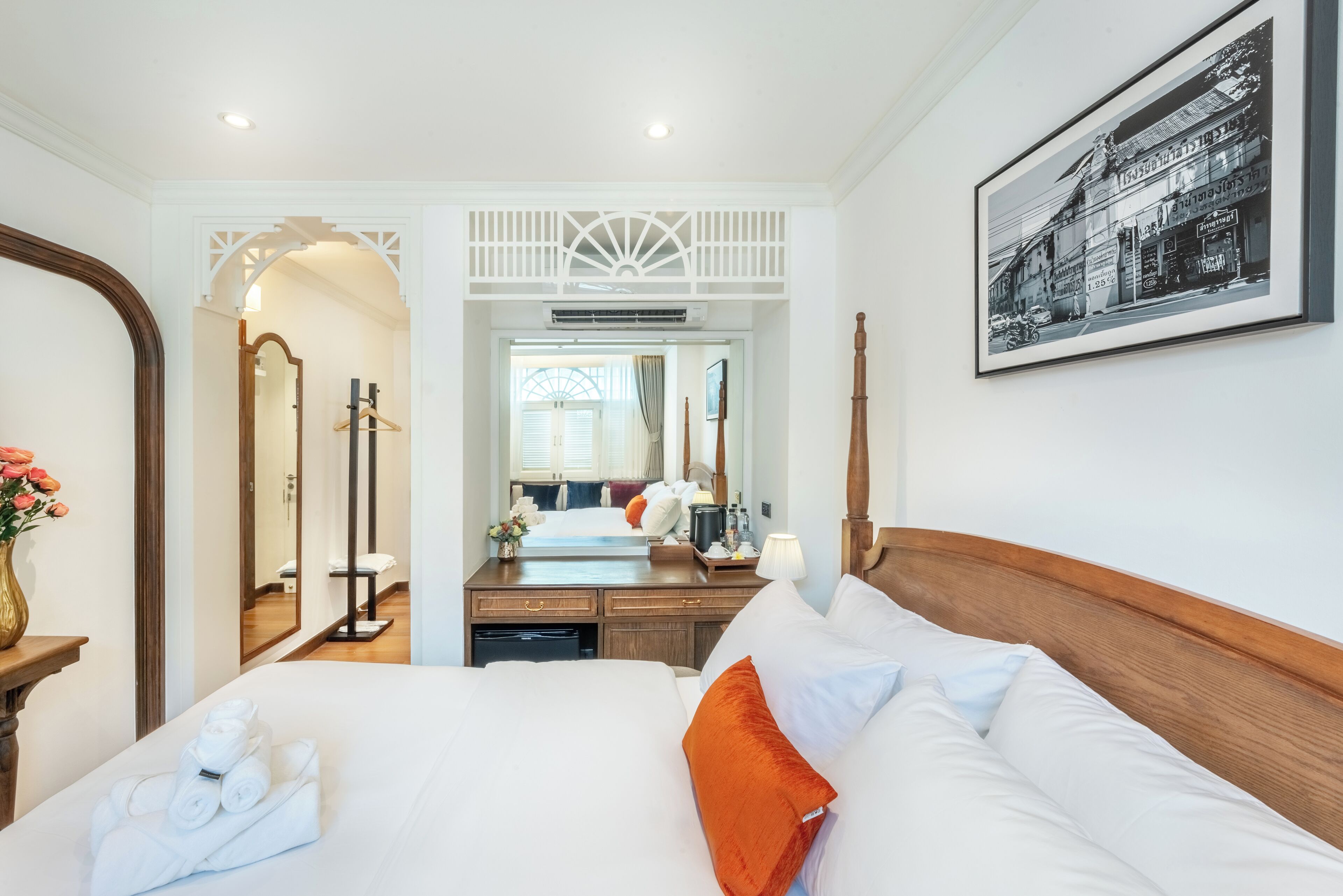 Habitación de hotel con una cama grande, cabecera de madera, escritorio con espejo y un cuadro en la pared.
