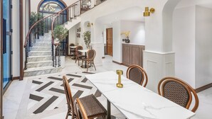 A spacious dining area with a marble table and wicker chairs, a staircase leading to an upper level, and a chandelier. - Cherie Bangkok Boutique Hotel (Bangkok)