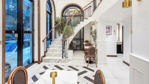 A spacious lobby with a marble floor, a staircase, and a dining area with wicker chairs. - Cherie Bangkok Boutique Hotel (Bangkok)