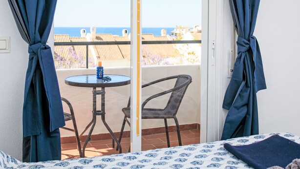 A balcony with a table and chairs, overlooking a beach. - Los almendros by Interhome (Rincón de la Victoria)