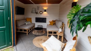 A cozy room with a sofa, a small table, a wall-mounted TV, and a decorative light fixture. - House 'n Cheese - Alkmaar (Alkmaar)