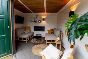 A cozy room with a sofa, a small table, a wall-mounted TV, and a decorative light fixture.