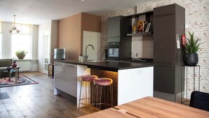A modern kitchen with a central island, bar stools, and a dining table. - House 'n Cheese - Alkmaar (Alkmaar)