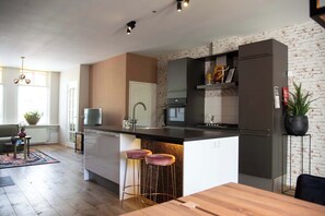 A modern kitchen with a central island, bar stools, and a dining table.