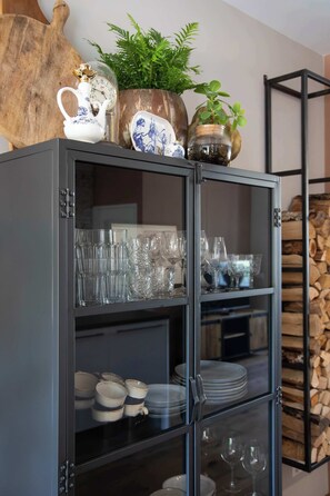 A cabinet with glass doors, containing various glassware and dishes.