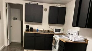 A kitchen with dark cabinets, a microwave, a stove, and a countertop with a coffee maker. - Hogan’s Hideout Bonnie Manor- Cozy Cottage to enjoy. (Eminence)