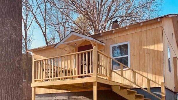 A wooden cabin with a balcony and a staircase leading to the main building. - Hogan’s Hideout Bonnie Manor- Cozy Cottage to enjoy. (Eminence)