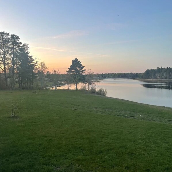 A grassy area with a body of water and trees in the background. - Private Waterfront Getaway (Richibouctou)