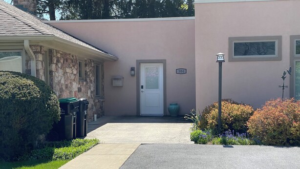Un edificio de dos plantas con fachada de piedra, puerta principal y buzón.