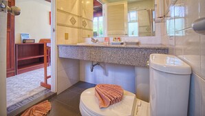 A bathroom with a granite countertop, a white sink, a mirror, and a toilet.