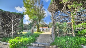 A pathway leading to a house surrounded by lush greenery and trees. - Les Cariatides by Interhome (Ile d'Oléron)