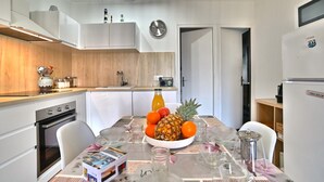 A modern kitchen with white cabinets, a wooden countertop, and a dining area with a table set for two. - Les Cariatides by Interhome (Ile d'Oléron)