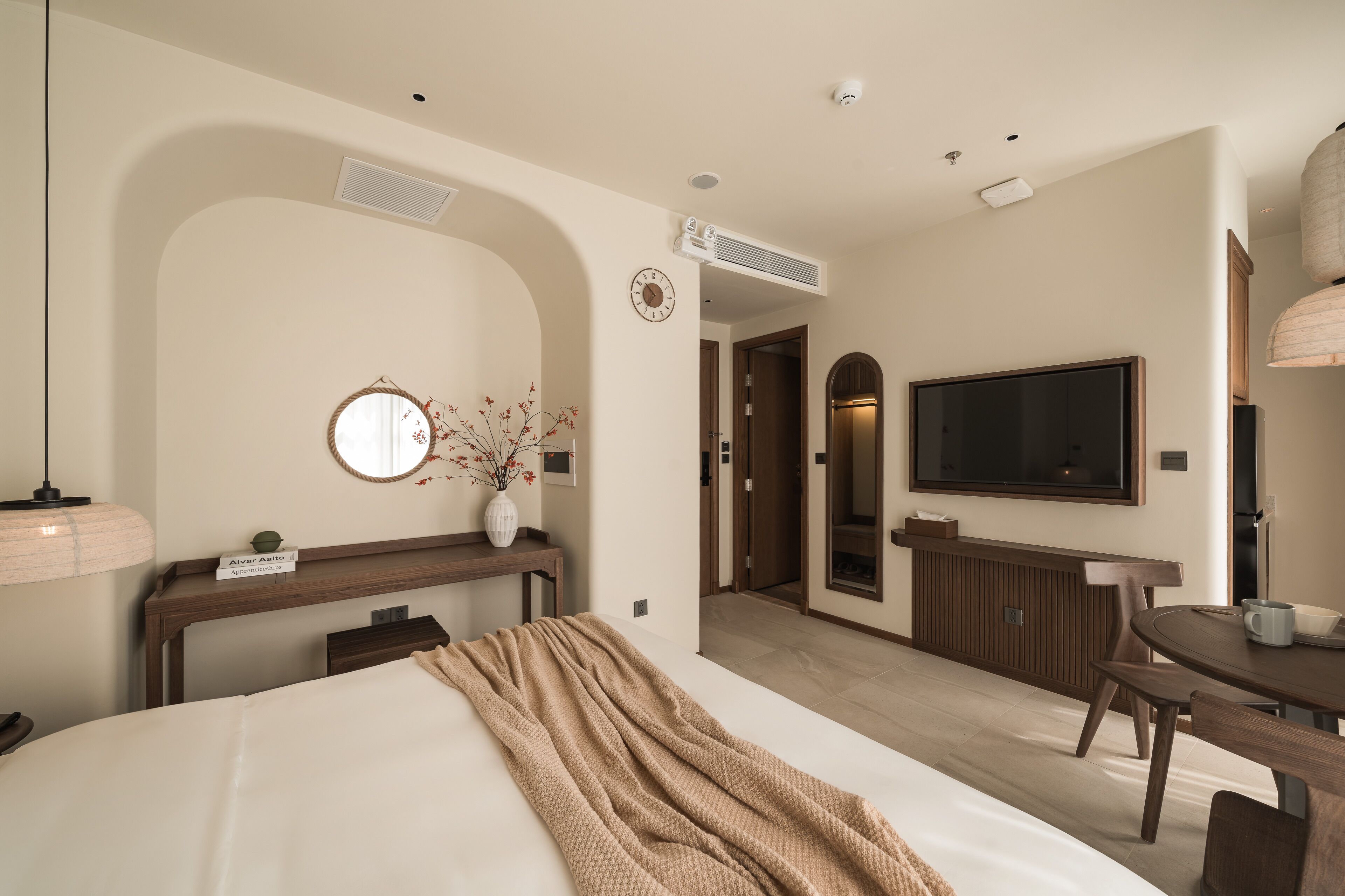 A hotel room with a bed, a desk, a TV, and a dining area.