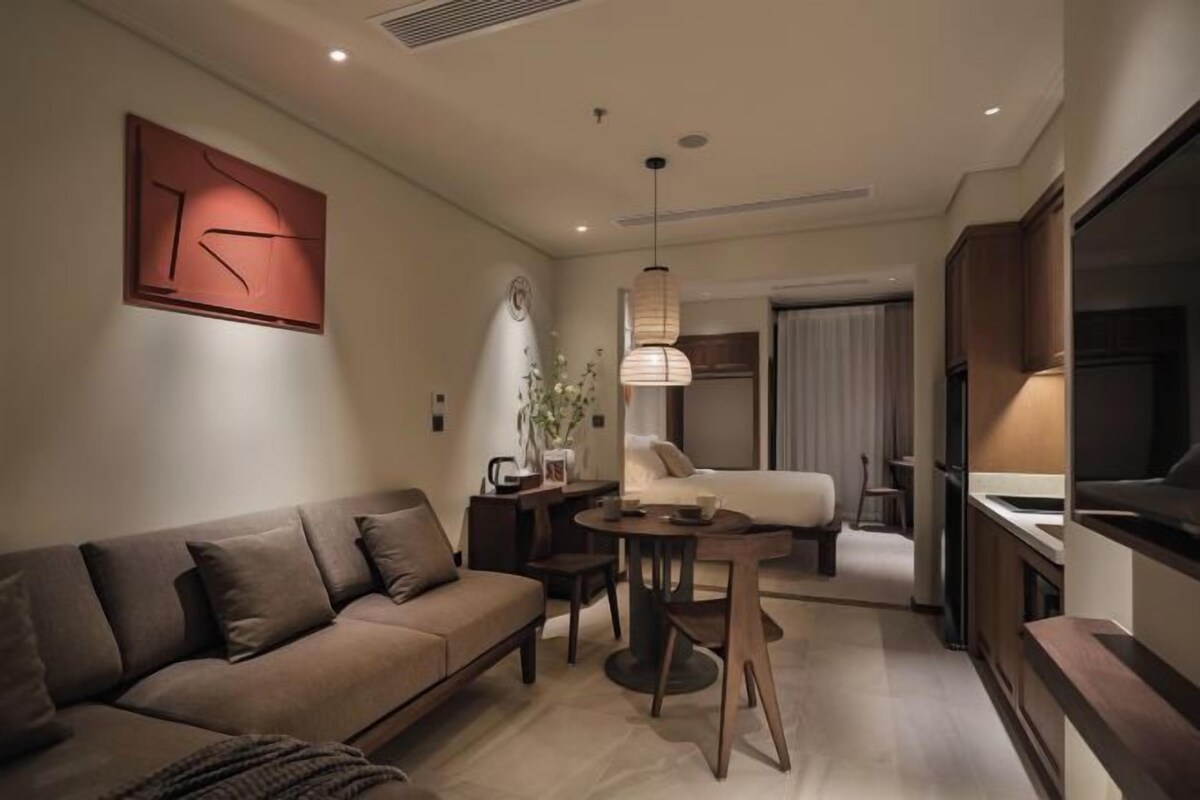 A modern living room with a sofa, a dining table, and a kitchen area.