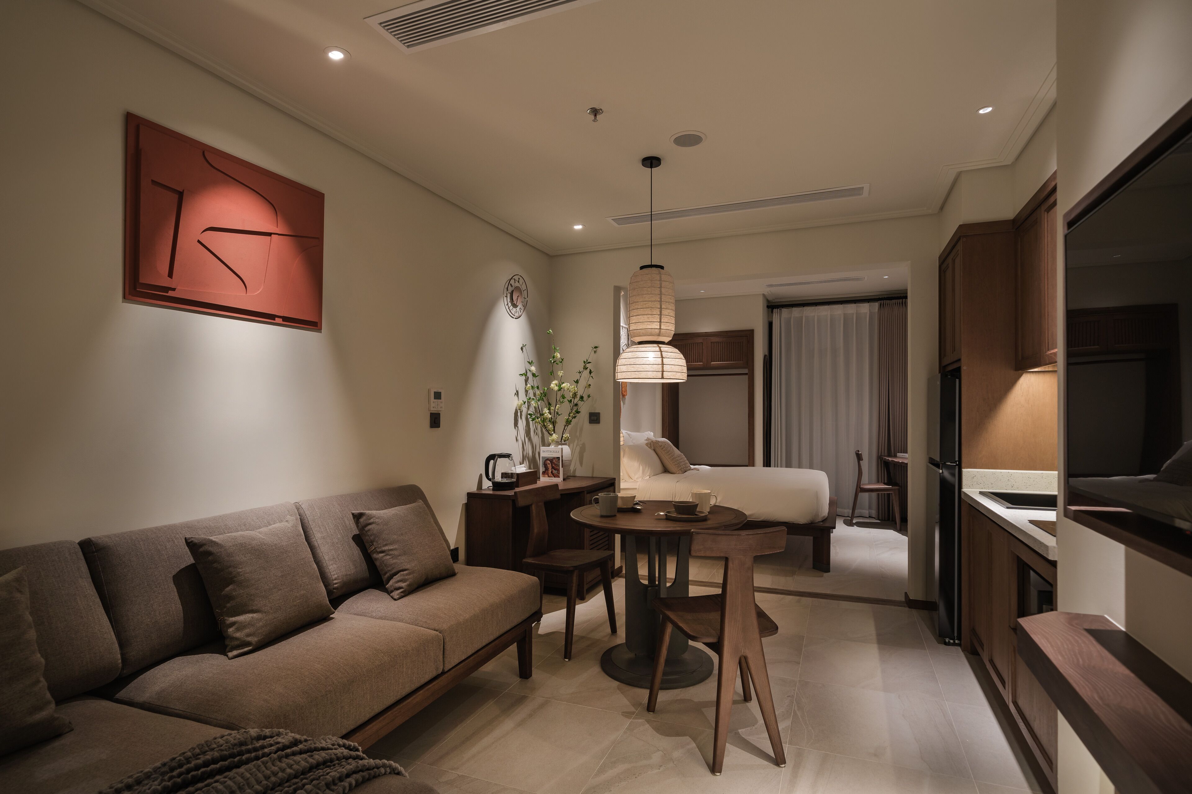 Een moderne woonkamer met een bank, een bijzettafeltje en een hanglamp.