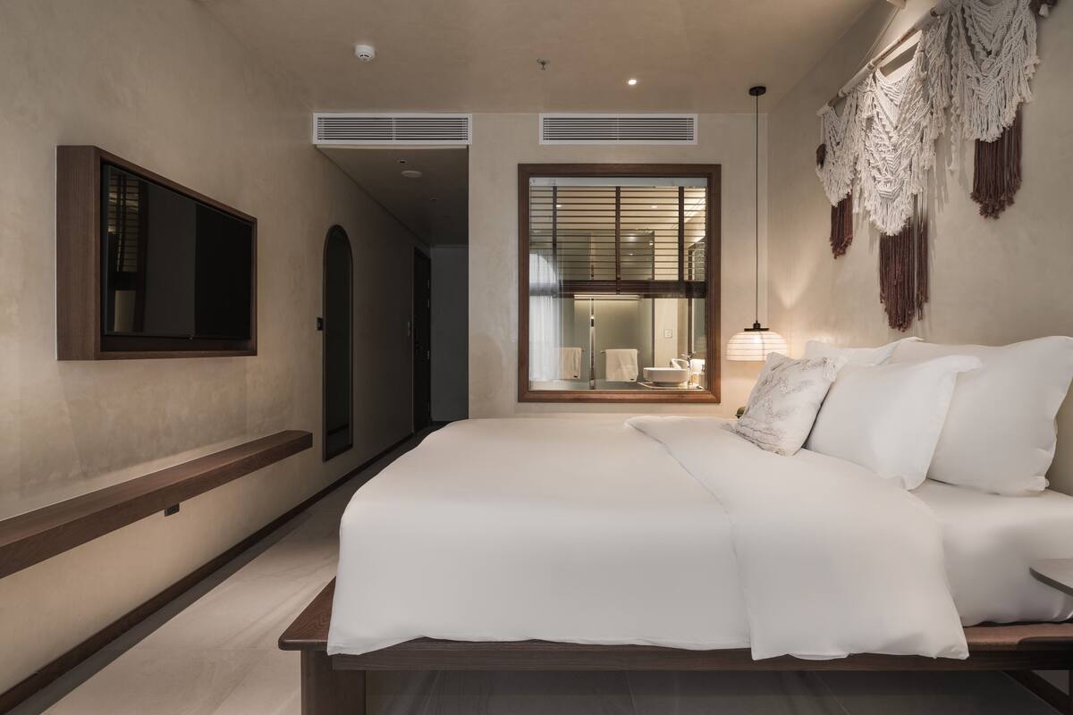 Un dormitorio moderno con una cama grande, un televisor de pantalla plana y una ventana con persianas.