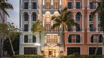 Un hotel de varios pisos con un diseño arquitectónico clásico, con ventanas y balcones arqueados.