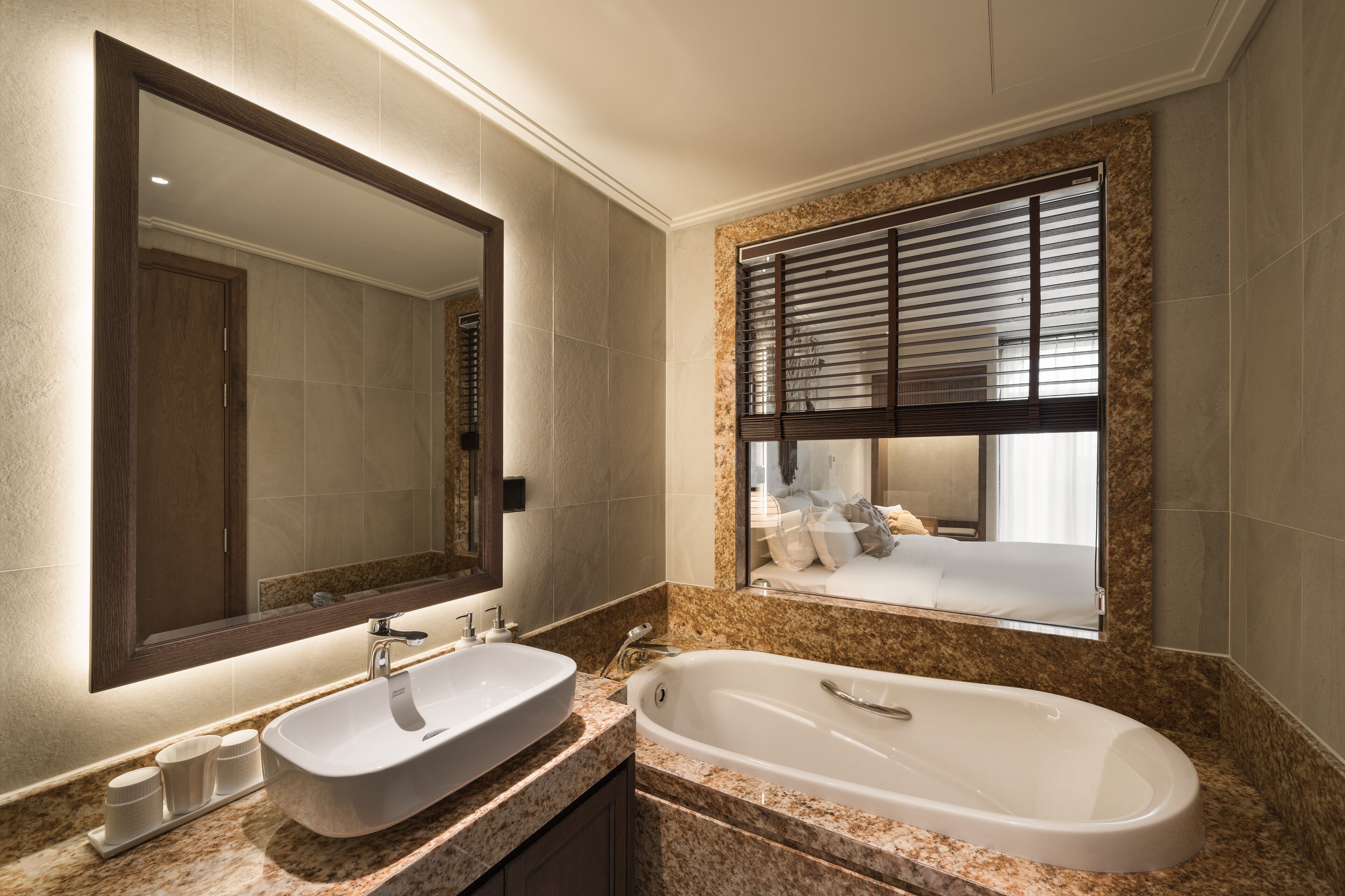 A modern bathroom with a large mirror, a sink, and a bathtub.