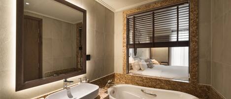 A modern bathroom with a large mirror, a sink, and a bathtub.
