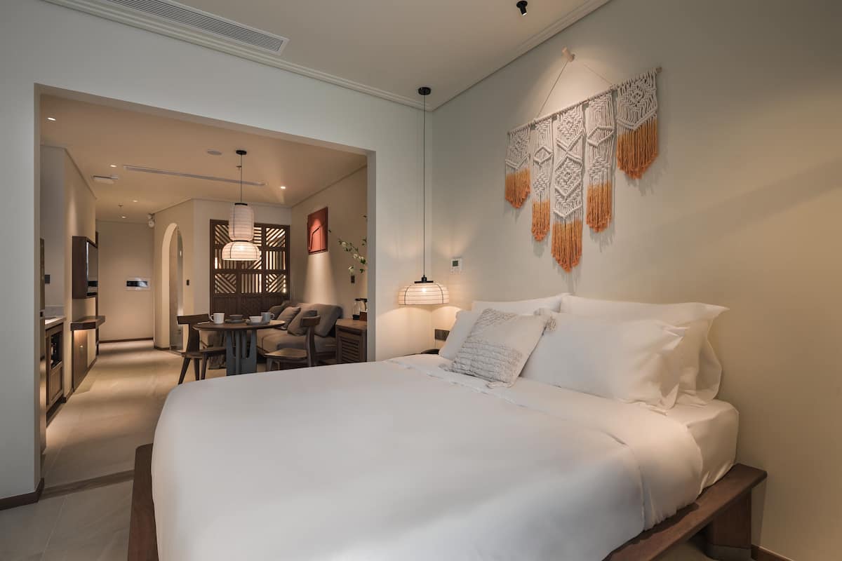 Una habitación de hotel moderna con una cama grande, un escritorio y un área de descanso.