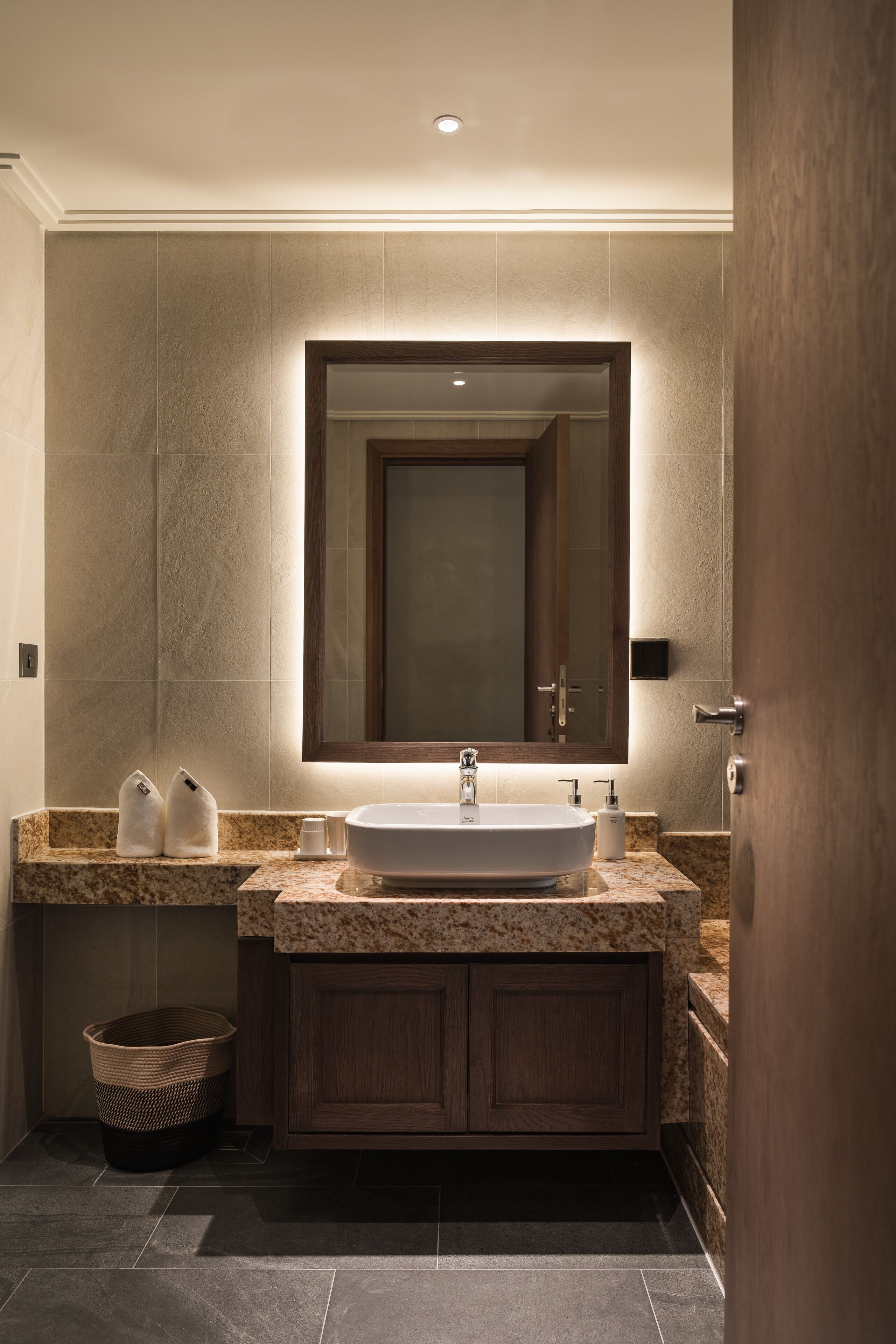 A modern bathroom with a large sink, a mirror above it, and a wooden cabinet below.