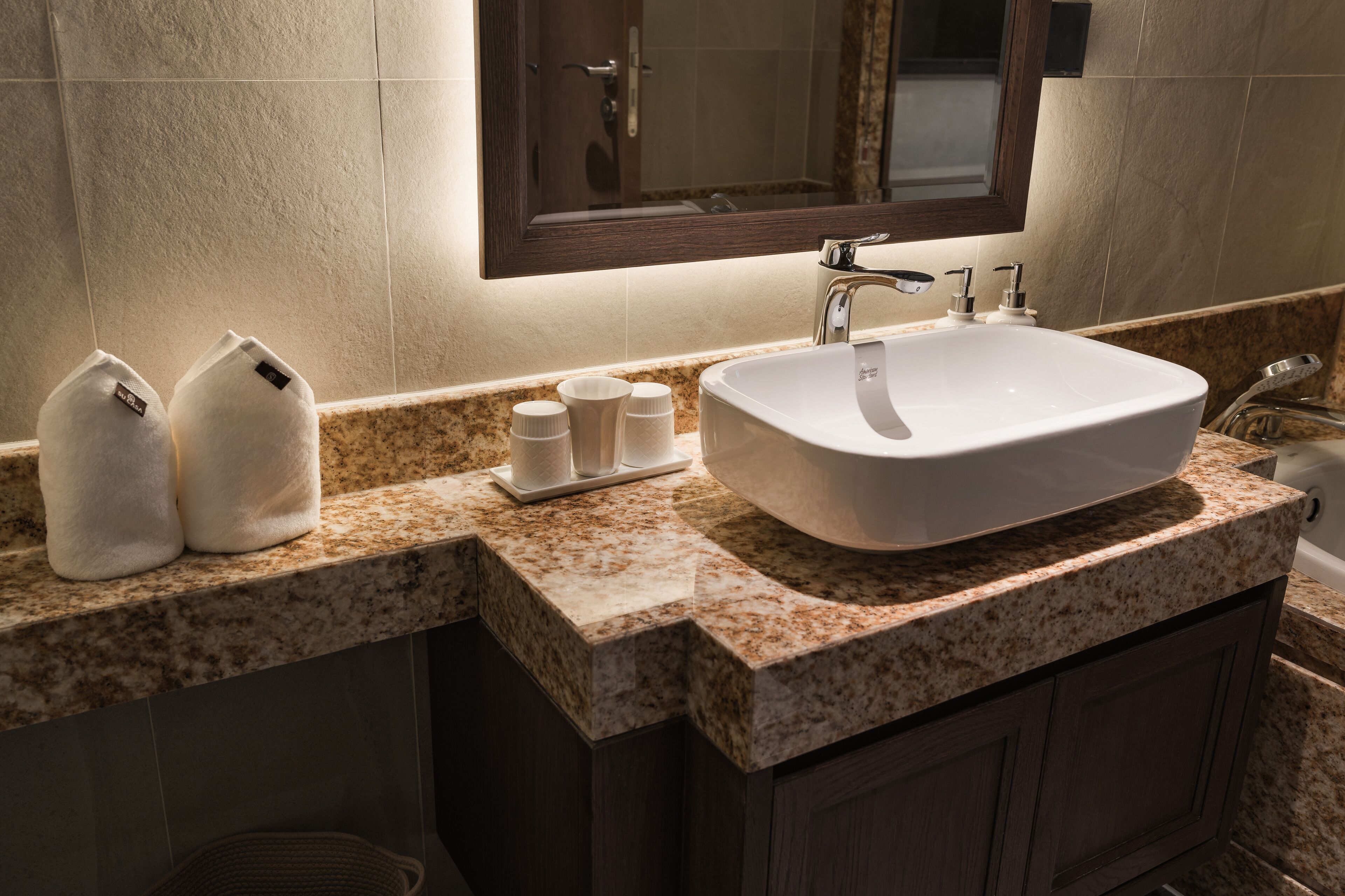 A bathroom with a white sink, two towels, and a mirror above the sink.