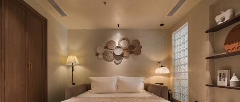 A bedroom with a large bed, a wooden wardrobe, a wall-mounted decorative item, and a window with patterned blinds.
