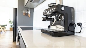 Moderni keittiö, jonka työtasolla on musta espressokone.