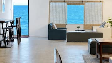 Un vaste espace de vie avec vue sur la mer, un coin repas avec des chaises et un canapé.