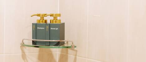 A bathroom with a glass shelf holding a shampoo and shower gel dispenser.