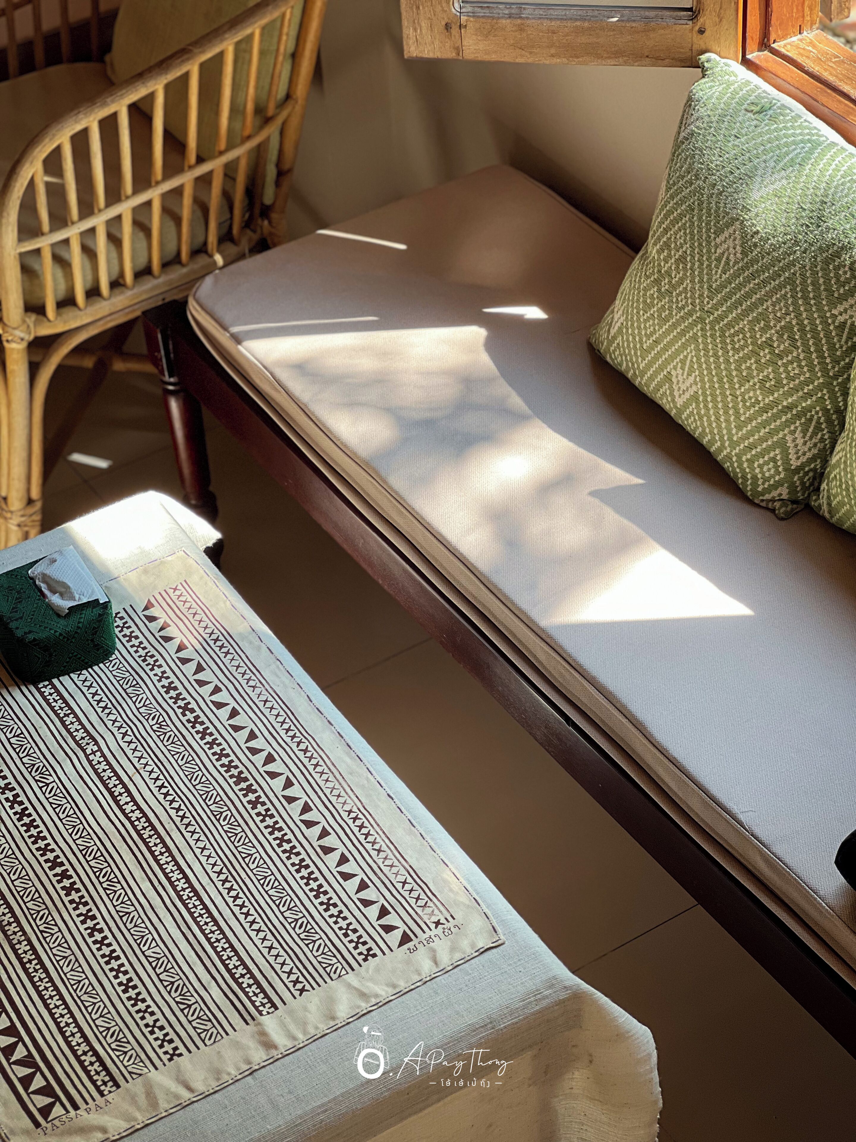 A small, cozy room with a wooden chair, a bench, and a sofa with a patterned cushion.