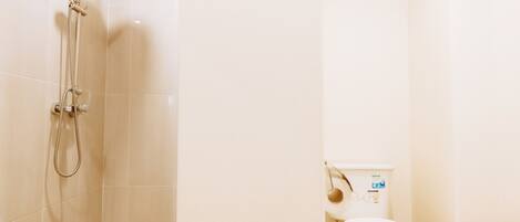 A shower with a wooden ceiling, a toilet with a white seat cover, and a basket on the floor.