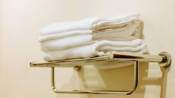 A stack of white towels on a metallic towel rack attached to a wall.