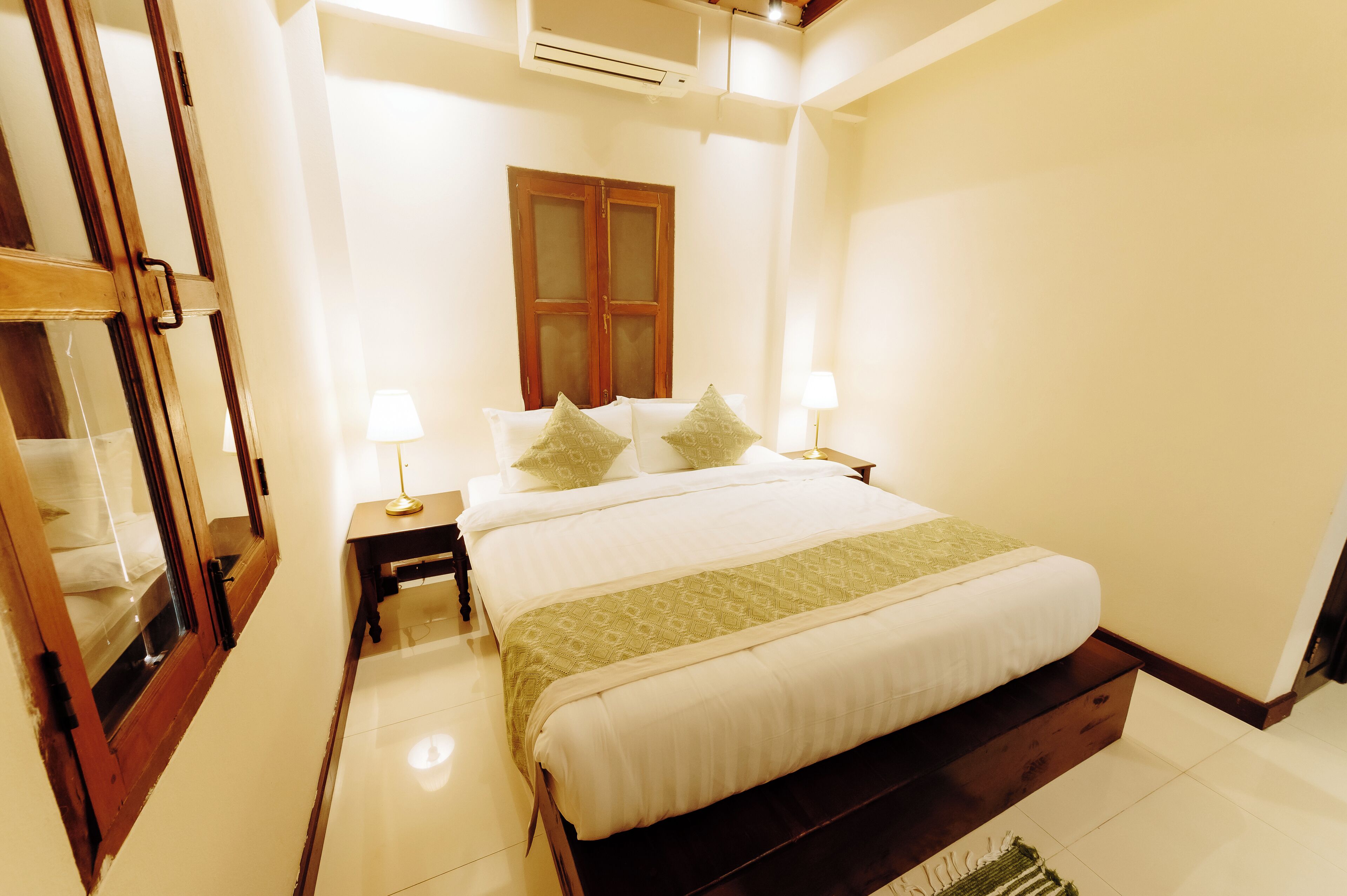 A neatly arranged bedroom with a bed, bedside tables, and a window.