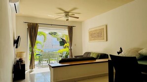 A room with a ceiling fan, a bed with pillows, a table with a lamp, and a view of greenery outside. - Gorgeous 8 People Basic Villa With Pool Playacar Phase 2 (Playa del Carmen)