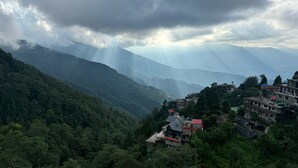 A mountainous landscape with a valley and scattered buildings. - Deoja Forest Stay (Darjeeling)