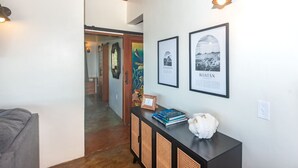 A hallway with a wooden ceiling, a black console table with books and a white sculpture, and framed pictures on the wall.