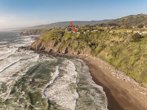 A coastal landscape with a sandy beach, rocky cliffs, and a small settlement with houses. - Oceanfront/ Stunning Views/ Hot Tub/ Contemporary (Manchester)