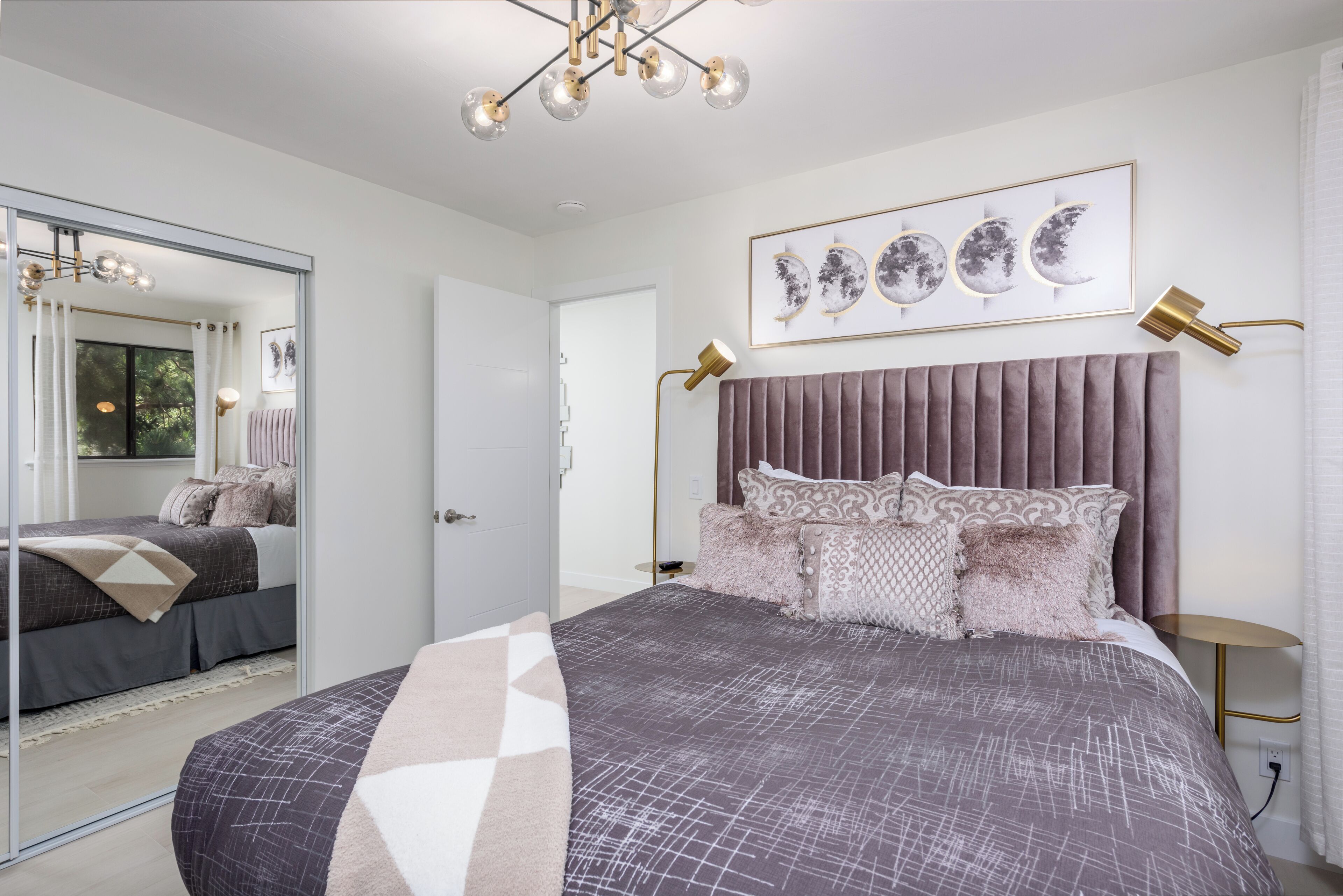 Une chambre à coucher moderne avec un grand lit, un miroir et un lustre.