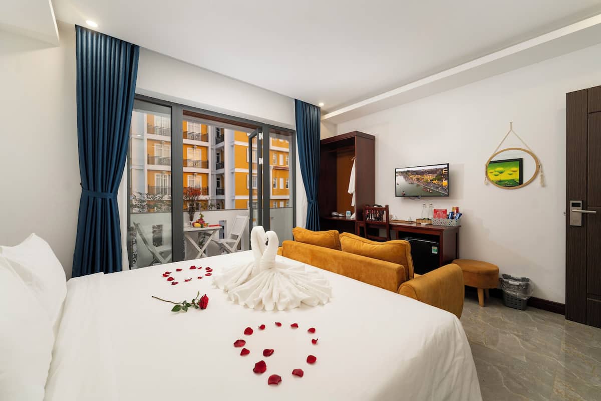 Une chambre d’hôtel avec un lit, un bureau, une chaise, une télévision et une vue sur un immeuble par la fenêtre.