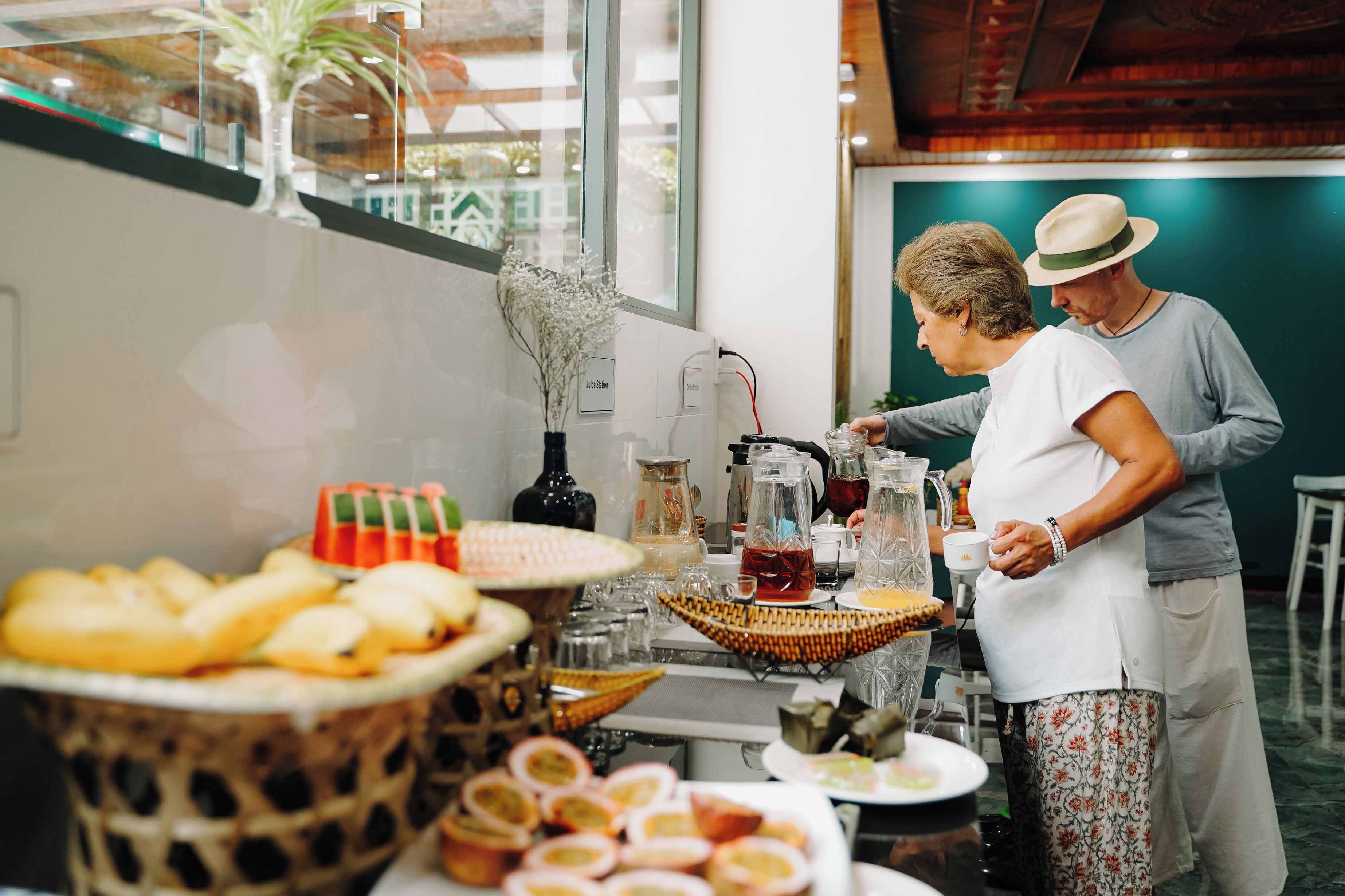 A buffet setup with various food items and beverages, a decorative plant, and a modern interior design.