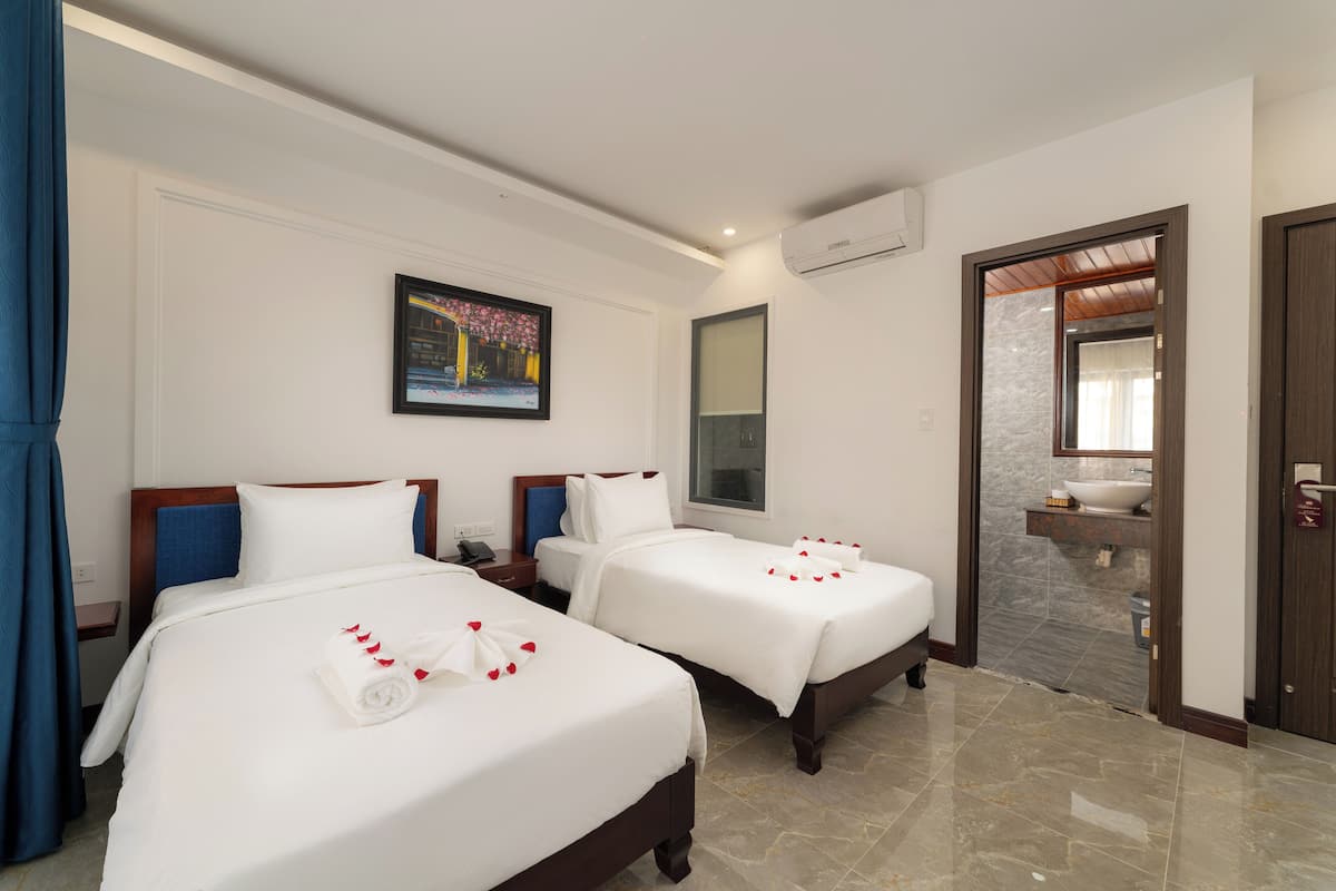 Une chambre d’hôtel avec deux lits, une salle de bain et un tableau au mur.